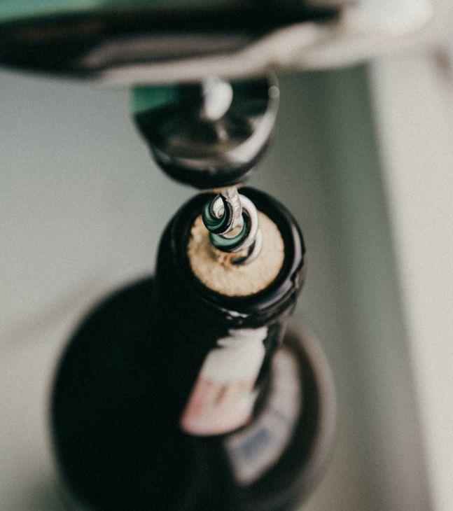 Above shot of a cork screw unscrewing a wine bottle
